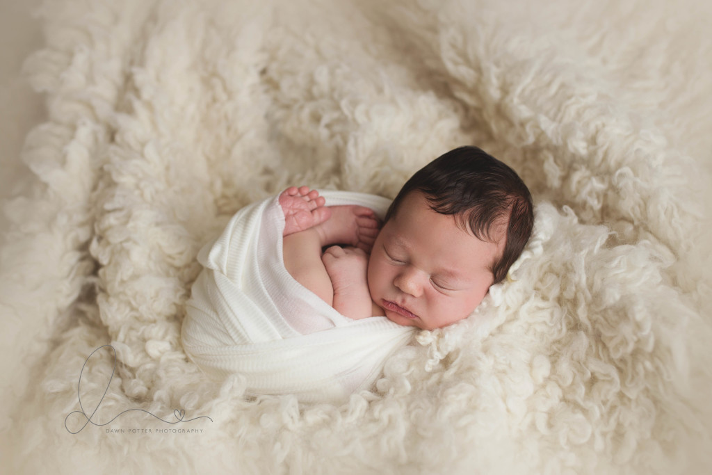 newborn baby boy wrapped on flokati